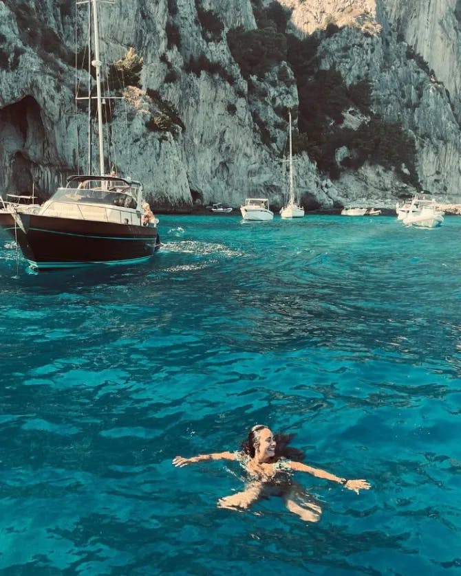 Travel advisor Amanda swimming in the ocean with boats in view