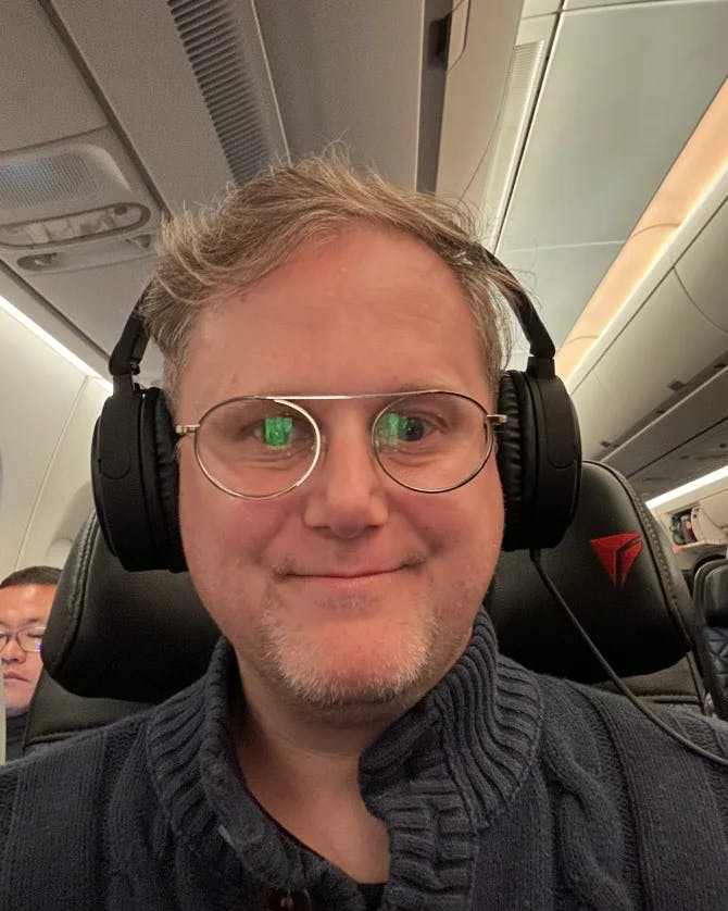Travel advisor Joshua sitting on a plane wearing headphones