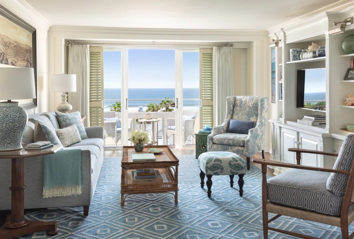 a living room with a blue rug and furniture overlooking the sea