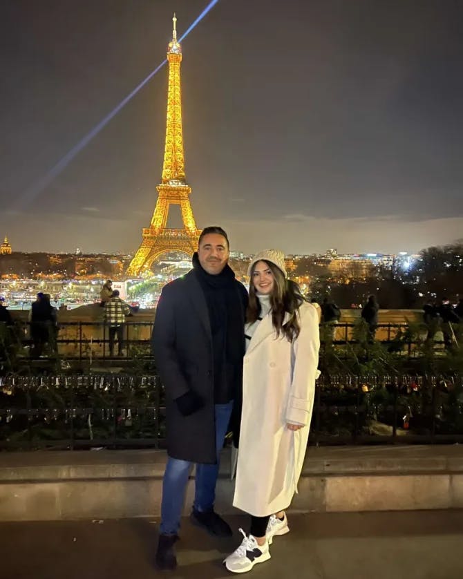 Travel advisor Riva Hanna posing for a picture with male companion at night with Eiffel Tower in view