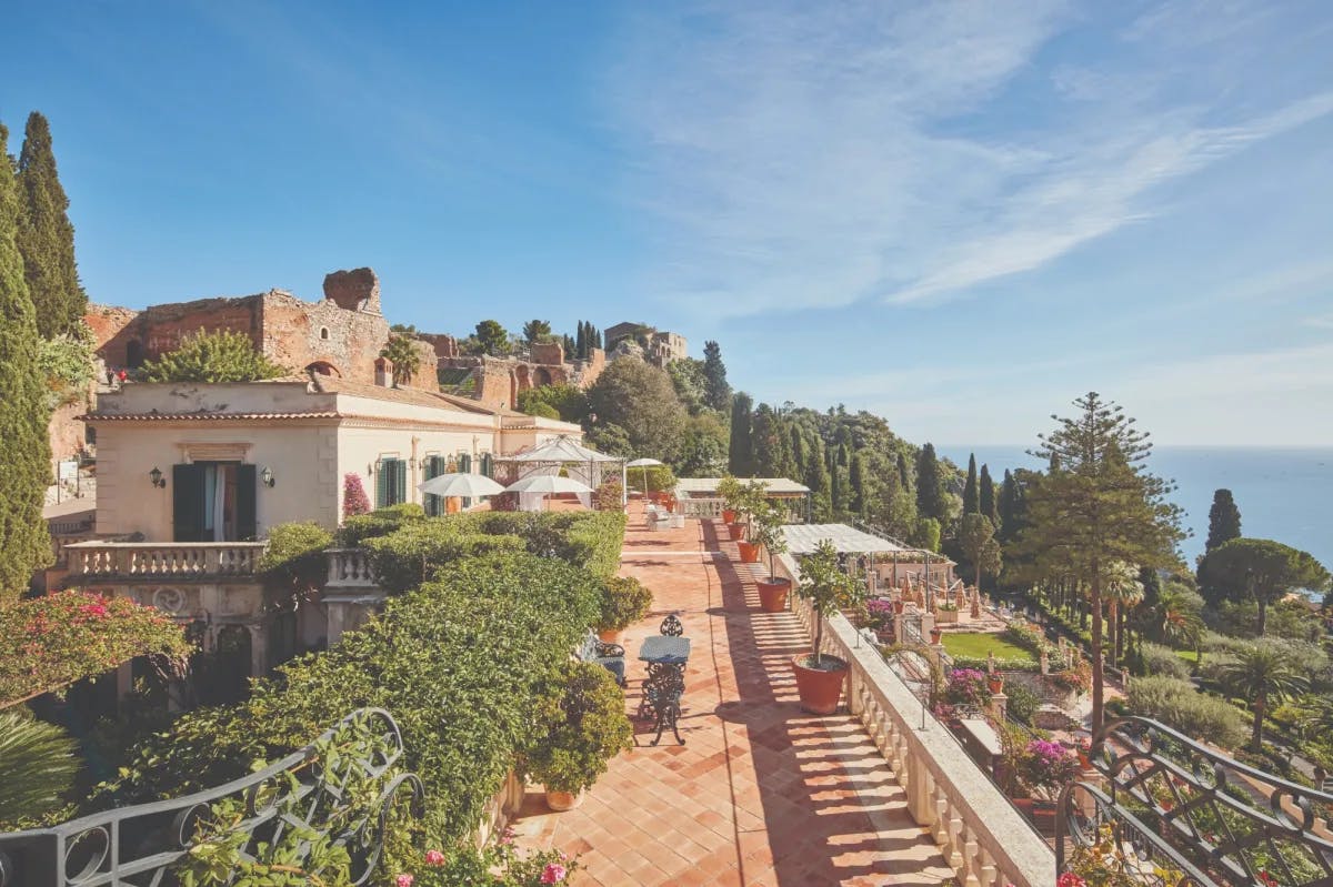 an elegant Italian terrace overlooking a lush garden and the sea
