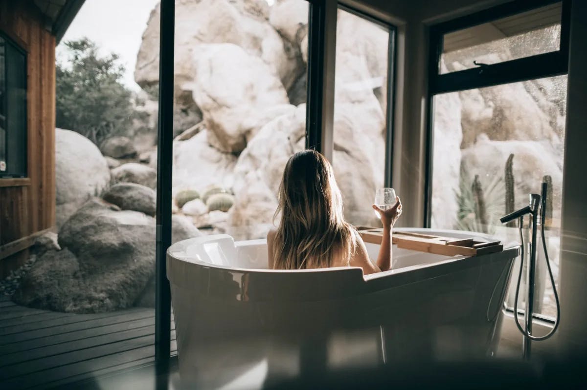 A woman sips a glass while sitting in a luxurious spa tub in a ritzy hotel room in Joshua Tree