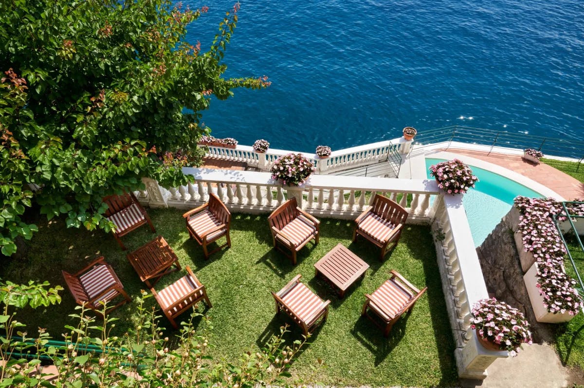 aerial view of square wooden tables and chairs on a grassy lawn overlooking the sea
