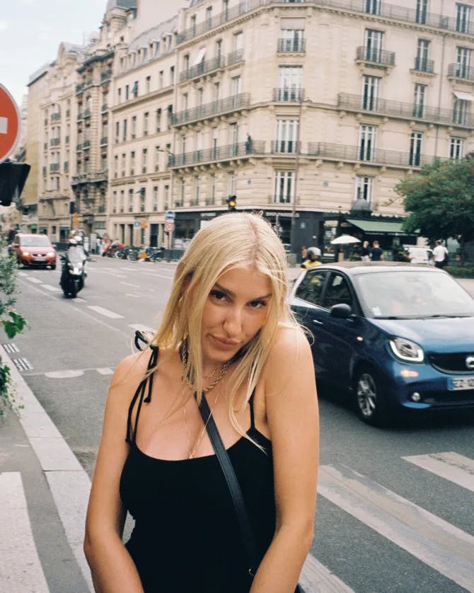 Travel advisor Olga posing in a black dress in a busy street with cars and old beige buildings