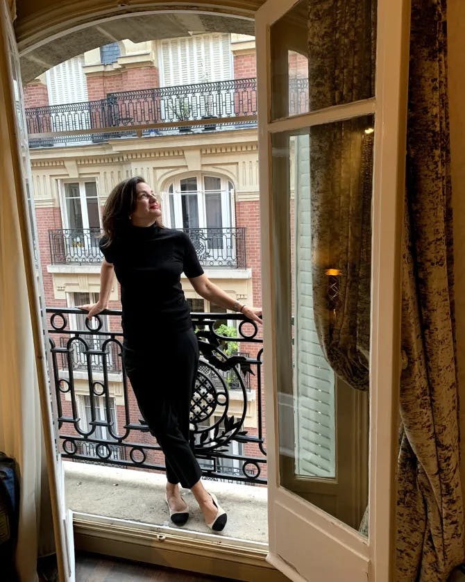 Travel advisor Rebecca standing on balcony of an old building in black dress