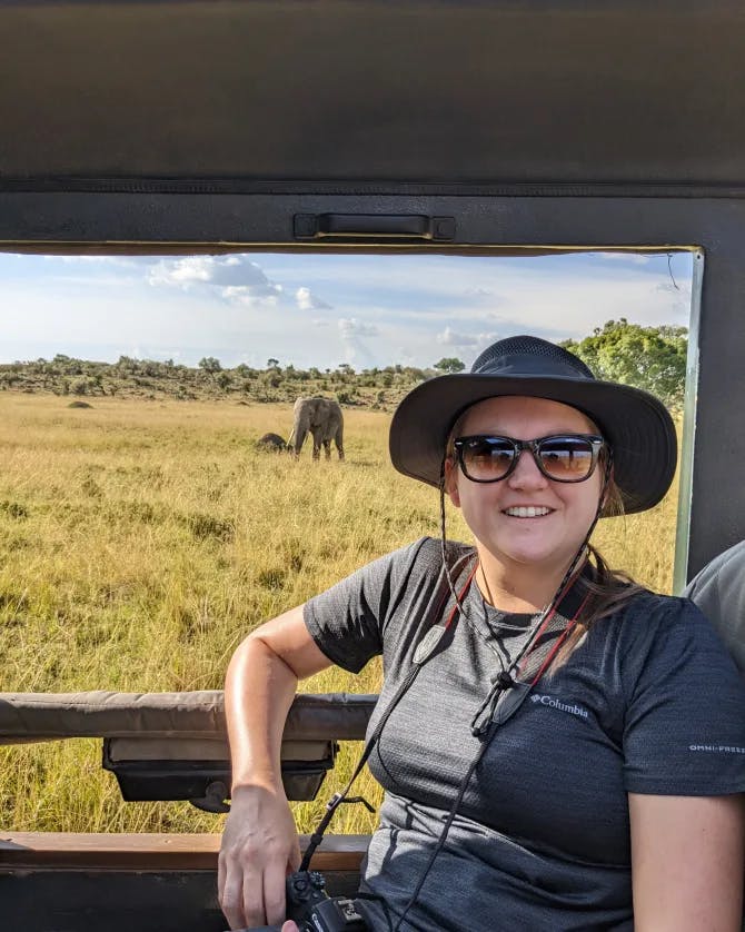 Travel advisor Paige in jeep wearing hat and sunglasses with elephant in view