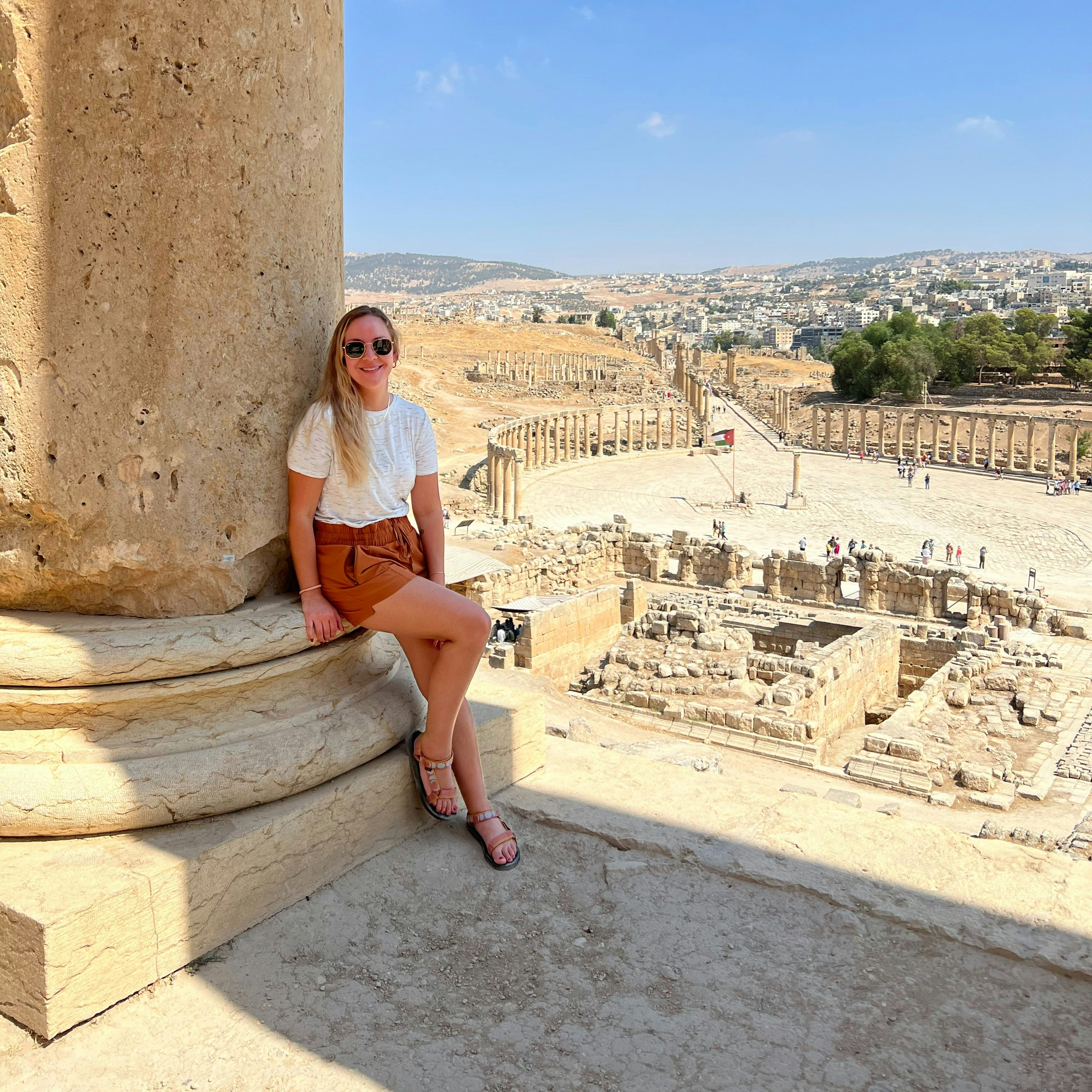 Travel advisor Kristen Wilkinson posing in white top against a pillar overlooking an ancient archeological site