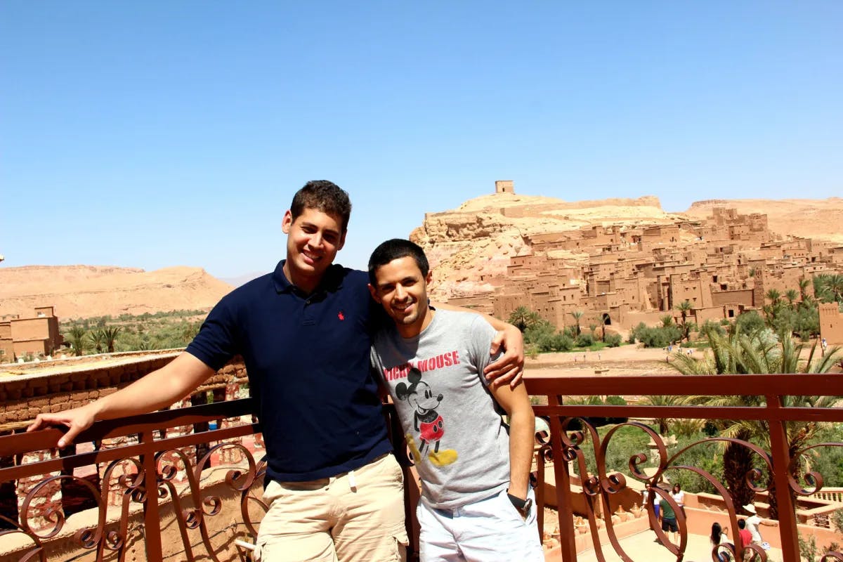 two young men stand next to each other in a desert on a sunny day