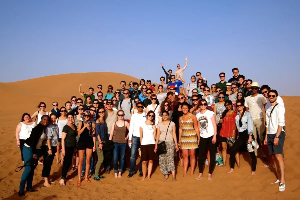a group of young business school students stand amidst a sandy desert