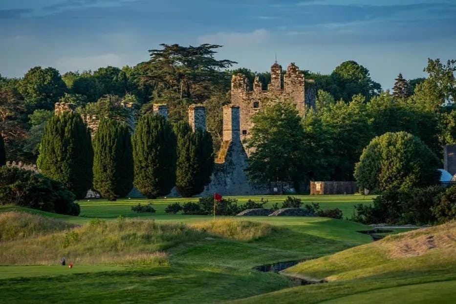 a green golf course with views of a stone castle