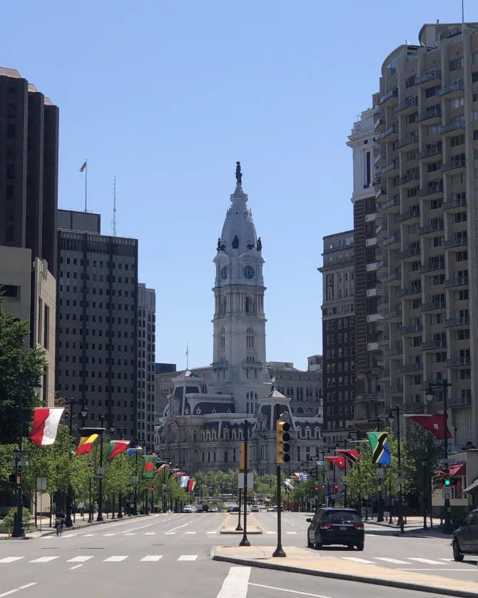 An view down an empty street with flags and a tall government building in the center. 