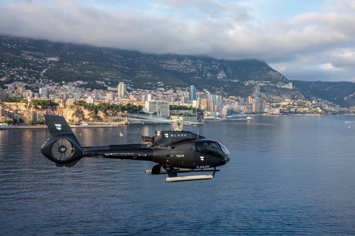 a black helicopter flies above a coastal city
