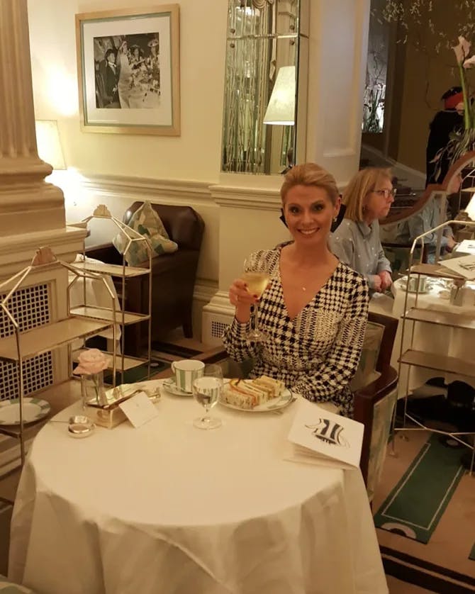 Travel advisor Megan Valente having a glass of champagne in a restaurant at a small round table with white tablecloth