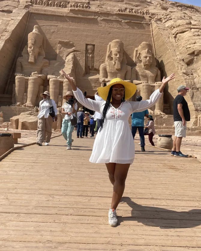 Travel advisor Charine in white dress and yellow hat posing in front of ancient ruins in Egypt