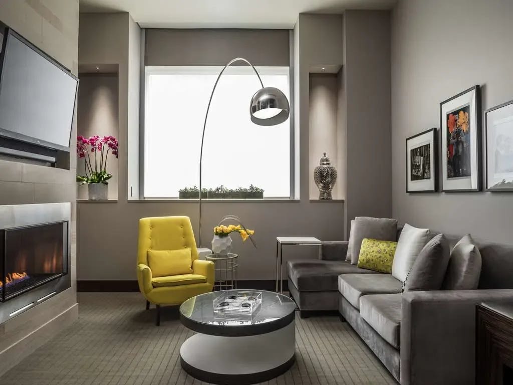 a seating area with a bright yellow chair and a curved metal floor lamp