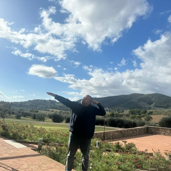 Picture of Rajiv enjoying nature with rolling green hills and a stone patio in the background on a sunny day