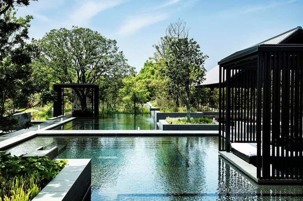 an expanse of pools flanked by sleek black canopy structures
