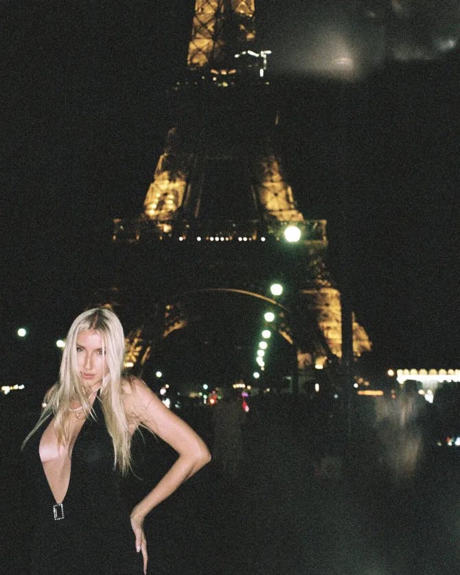 Travel advisor Olga in a black dress posing for a photo in front of Eiffel Tower at night