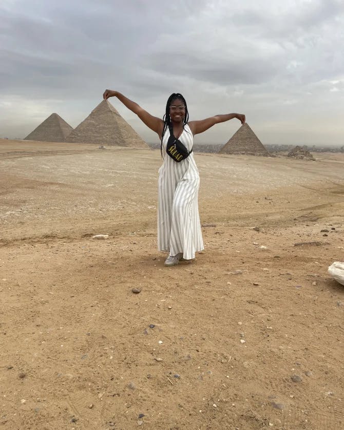 Travel advisor Charine in a white dress posing with pyramids in view