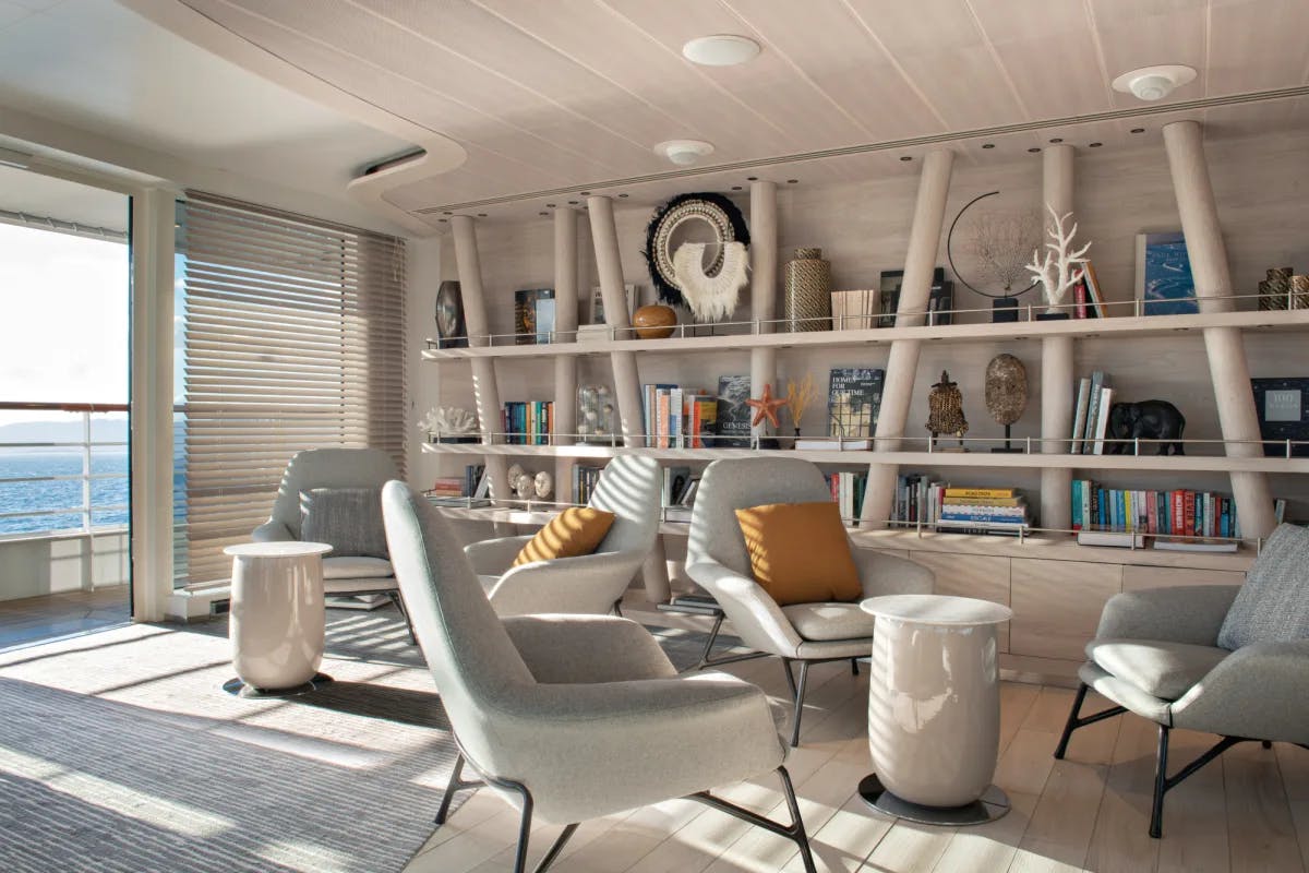 a white, airy living room on a cruise ship with a white multi-level bookcase