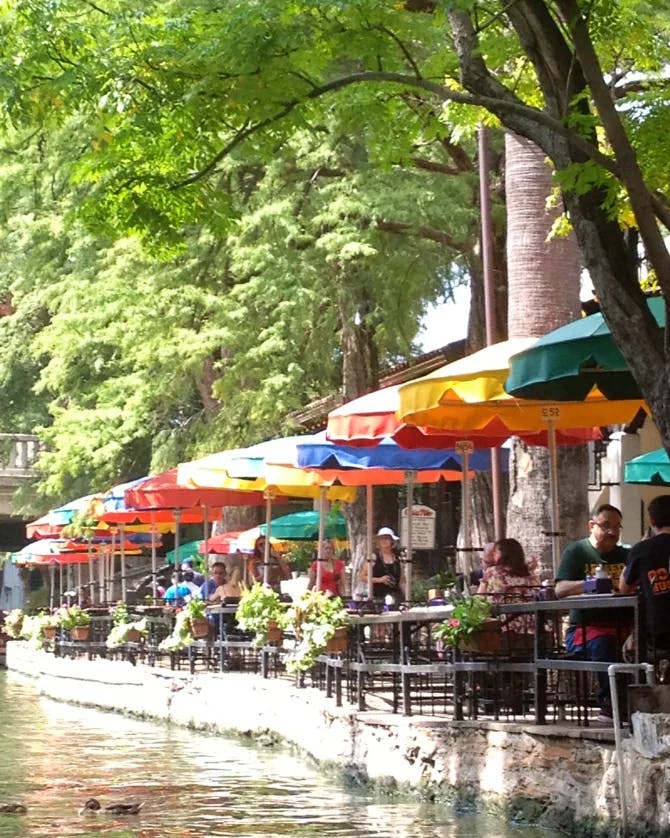 Picture of a body of water with colorful umbrellas and seating. 