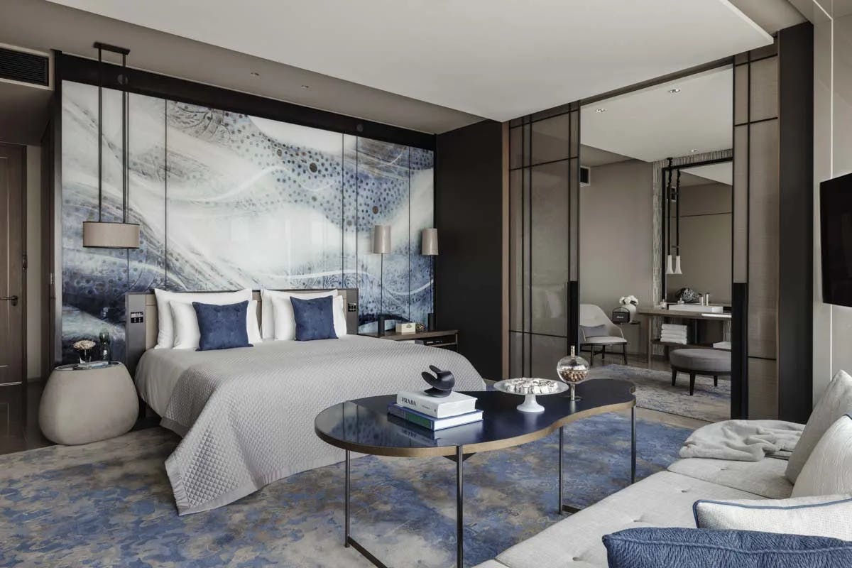a sleek hotel room with a bed adorned with gray blankets and blue pillows