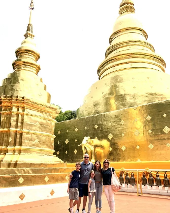 Ashley and her family posing for a photo with golden buildings in the distance. 