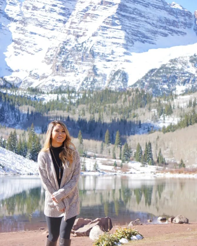 Travel advisor Truc posing for a photo in front of lake and snow.-capped mountains