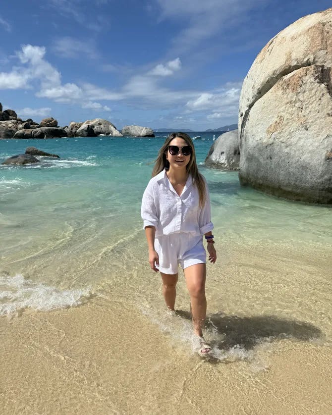 Travel advisor Truc posing for a picture in white outfit and sunglasses on the beach