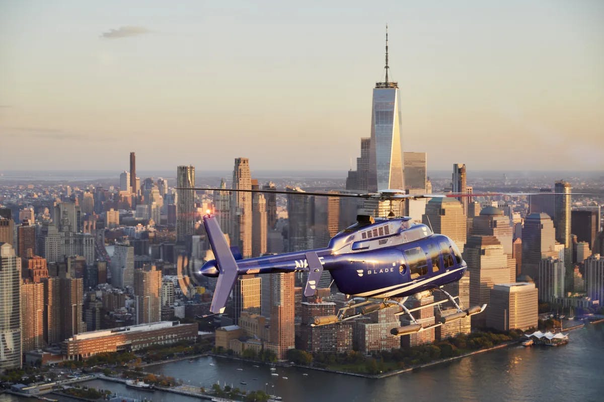 a blue helicopter flies above a city