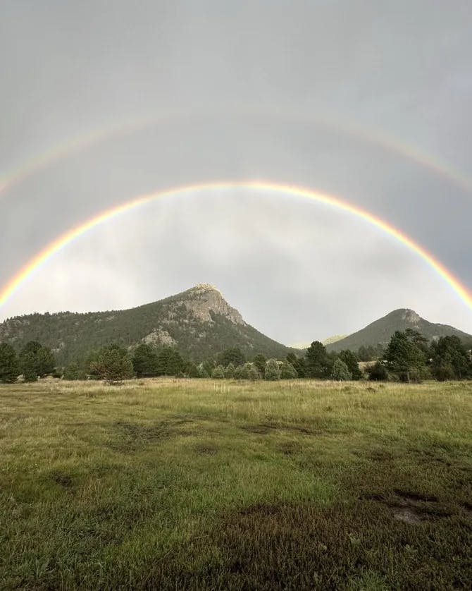 Beautiful view of double rainbow over a field and mountains