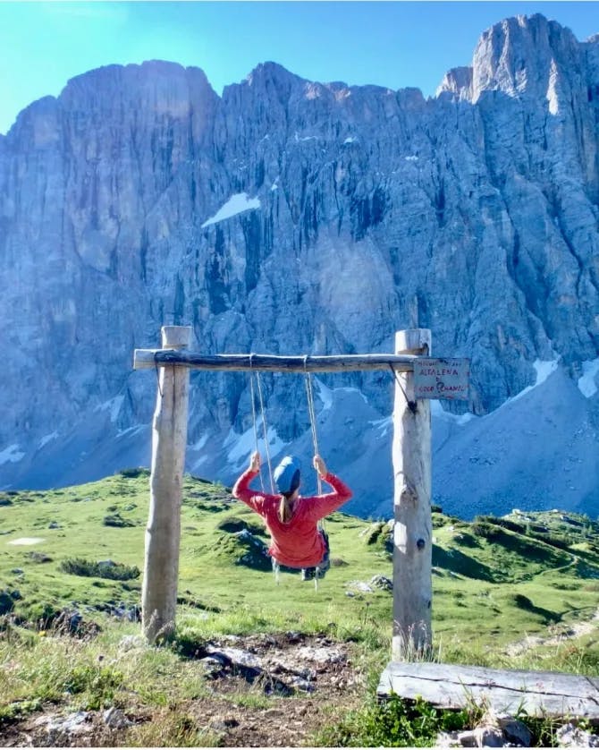 Travel advisor Ruth on a swing with mountains in view