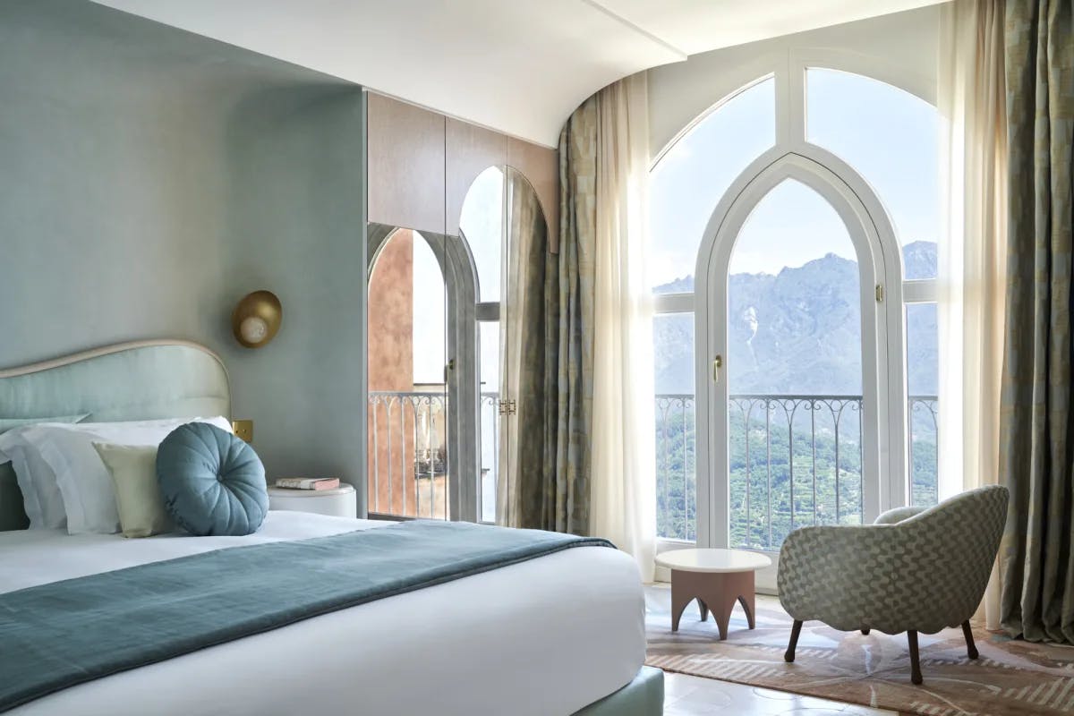 a serene bedroom with teal-blue walls and a large window overlooking a lush mountainous landscape