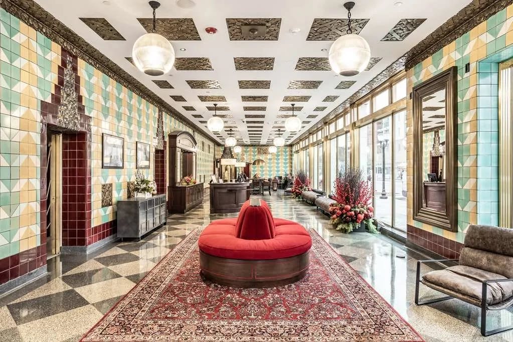 an opulent lobby with a circular red couch and tiled floors and ceilings