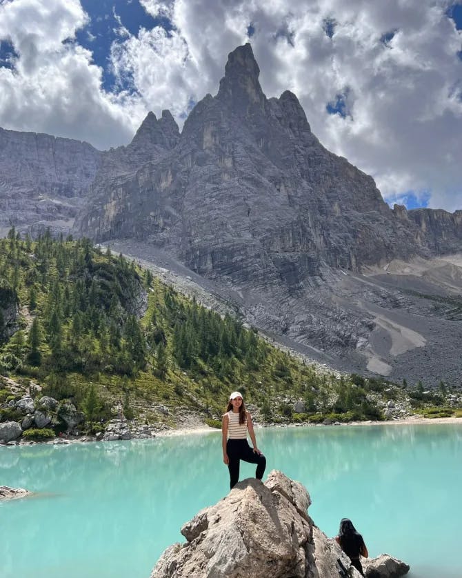 Travel advisor Sharon standing on a rock by a lake with mountains in view