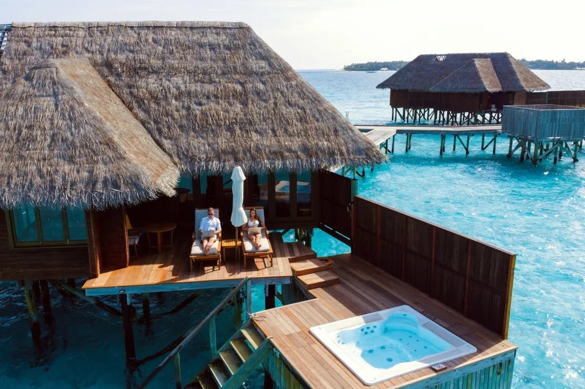 A working couple works on their laptops from the lavish comforts of a gorgeous overwater resort in the Maldives