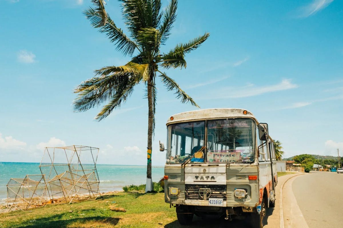 An old tour bus parked at a beach on a sunny day in Jamaica
