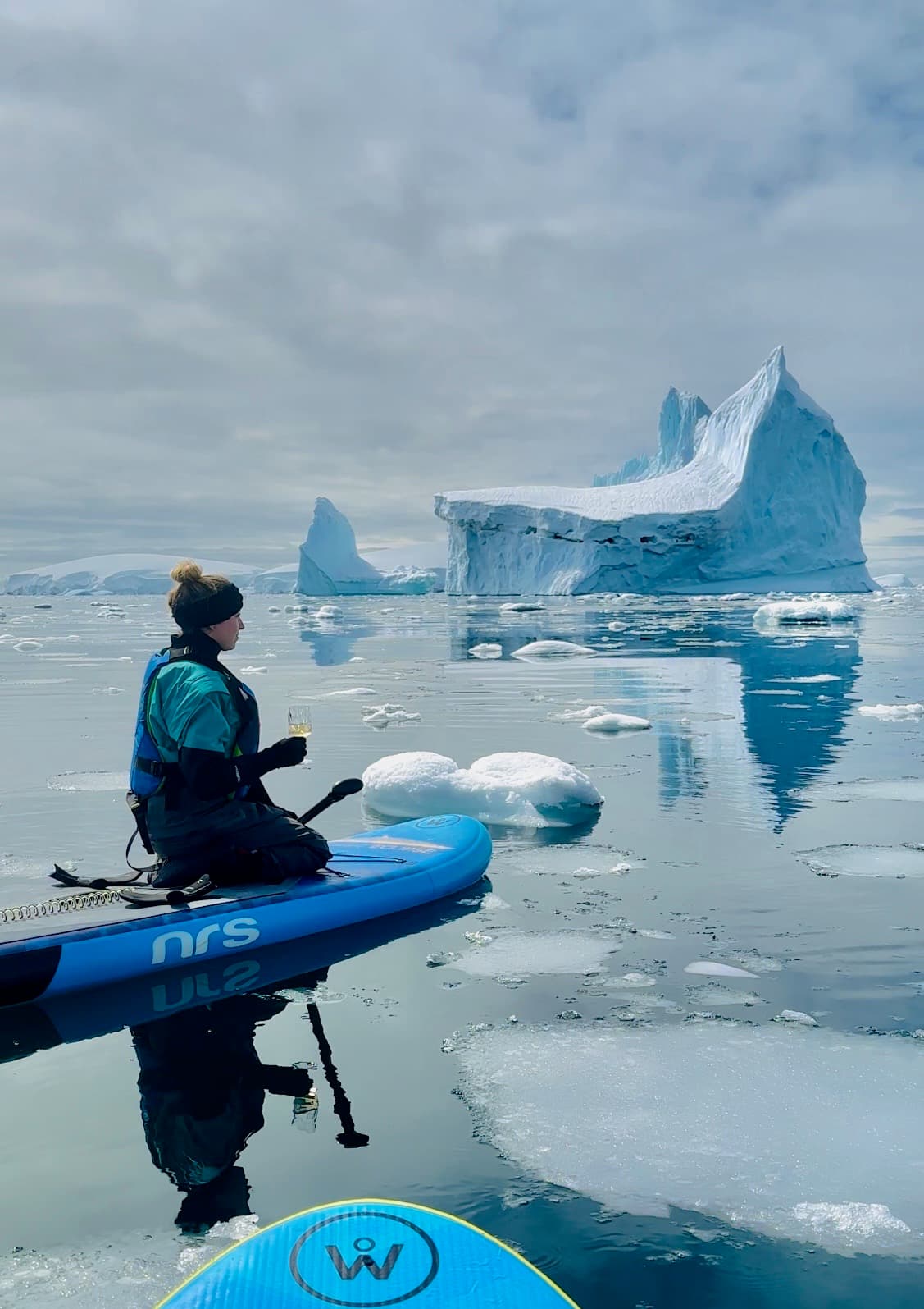 A person on a paddleboard in ice-filled water during the daytime