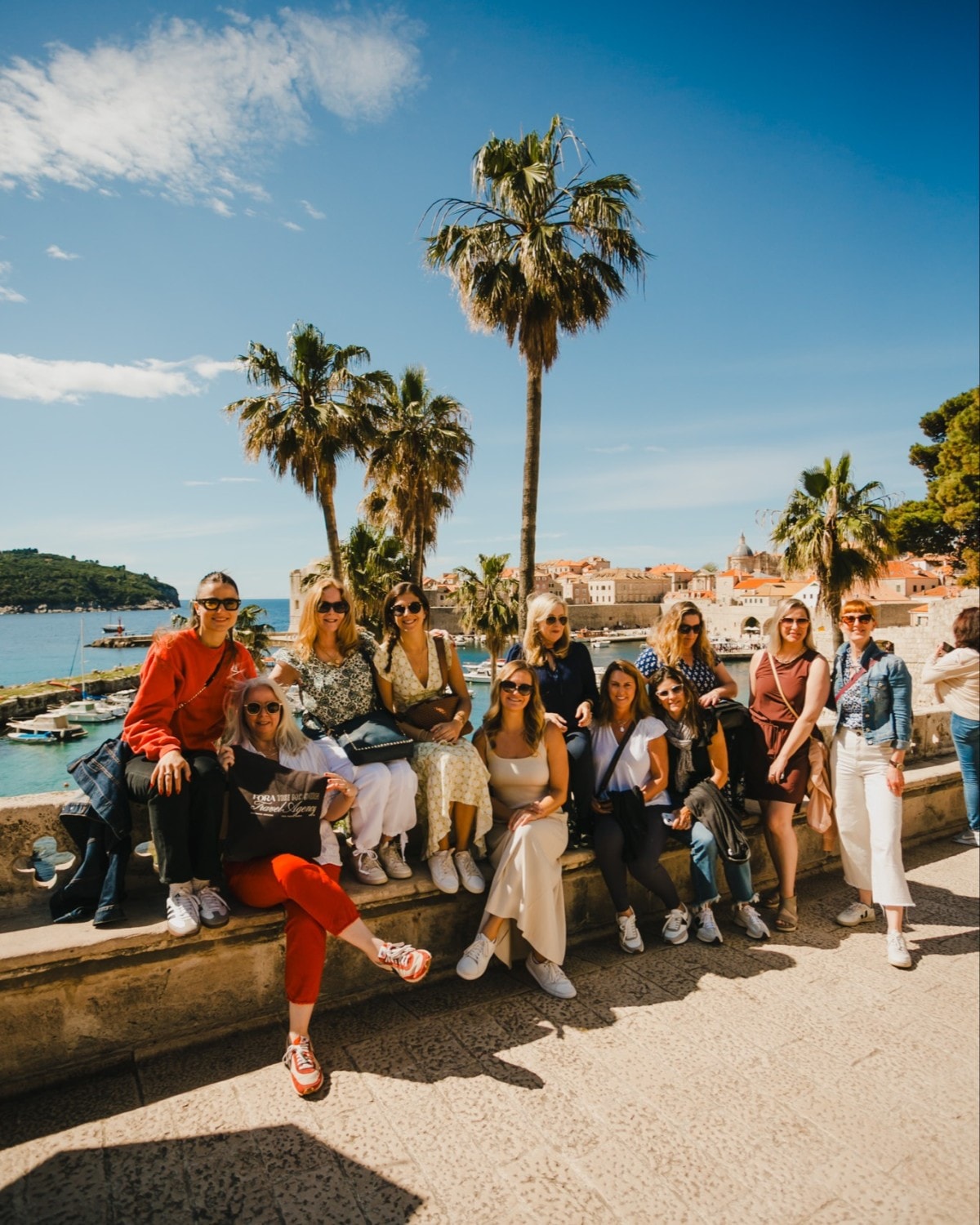 a group of people sit on a stone wall in Croatia