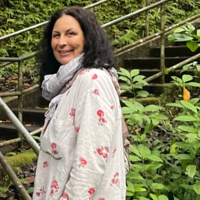 Travel advisor Suzanne in white dress posing on stairs surrounded by greenery