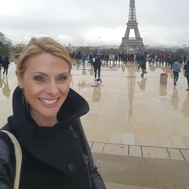 Travel advisor Megan Valente in a black coat with the Eiffel Tower in view