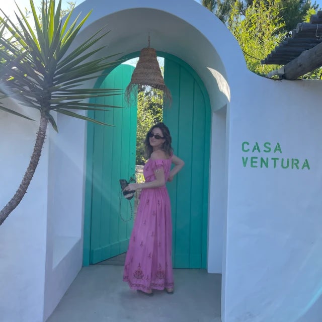 Alexa Scully in a pink dress in front of a green doorway and white building