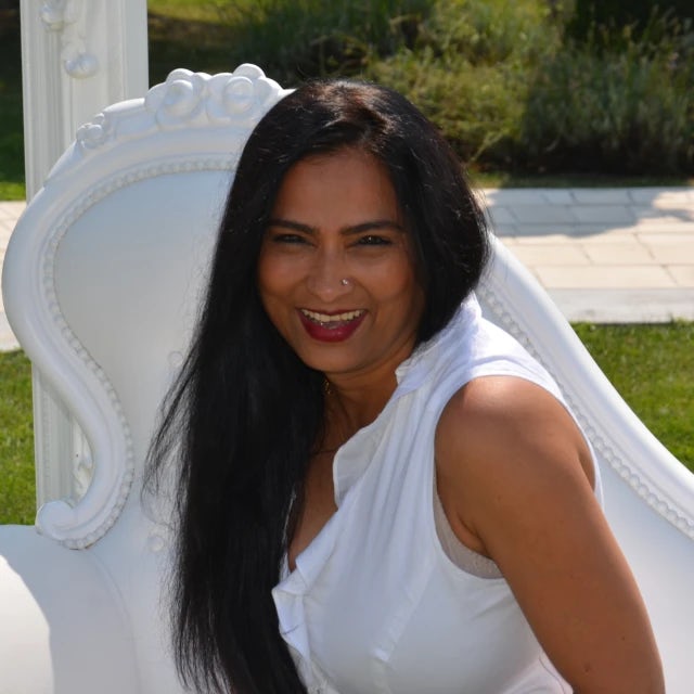 Travel Advisor Shalini Joshi in a white shirt sitting on a white bench.