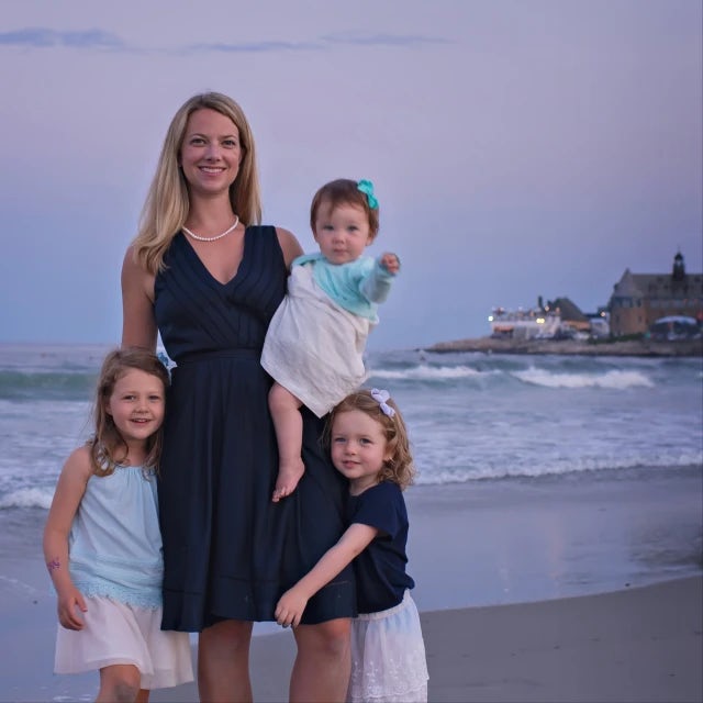 Jillian Kitson posing for a picture on the beach in the evening with three children