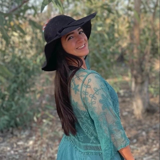 Picture of Ashley in a blue dress and black wide-brimmed hat in the woods