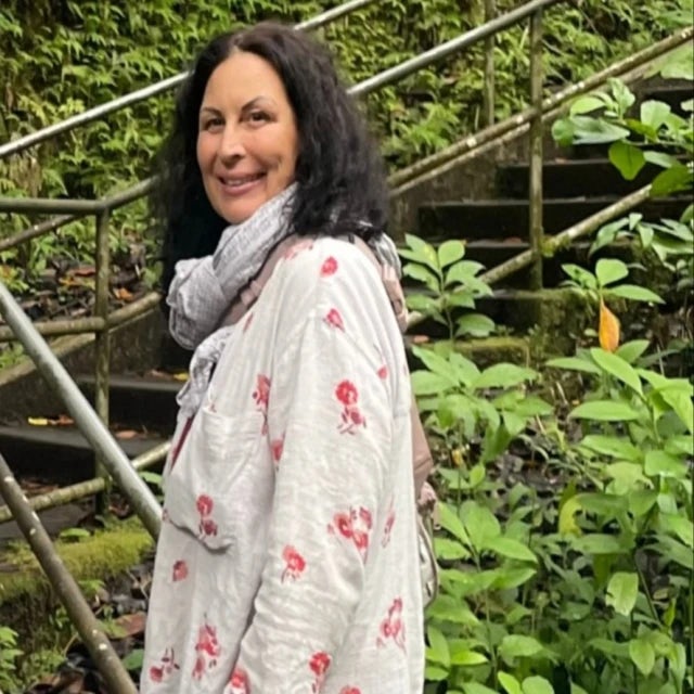 Travel advisor Suzanne in white dress posing on stairs surrounded by greenery