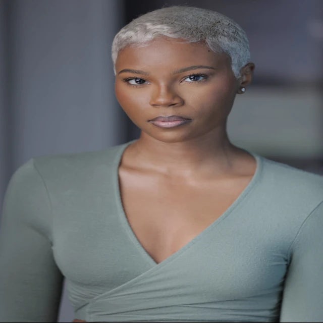 young woman with cropped silver hair wearing a sage top
